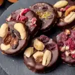 Mendiants au chocolat garnis de fruits secs et noix sur une assiette