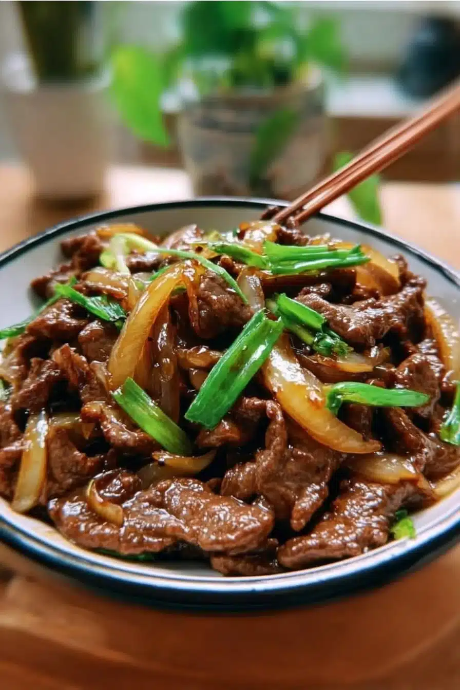 Plat de Bœuf Sauté aux Oignons servi avec des légumes frais.