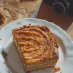 Un gâteau patate douce moelleux et doré, décoré de noix et de fruits sur une assiette.